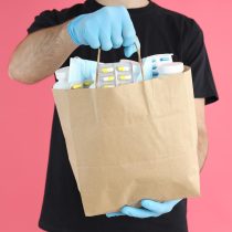 delivery-man-holds-bag-with-medicines-on-pink-back-2021-12-10-06-10-07-utc_c